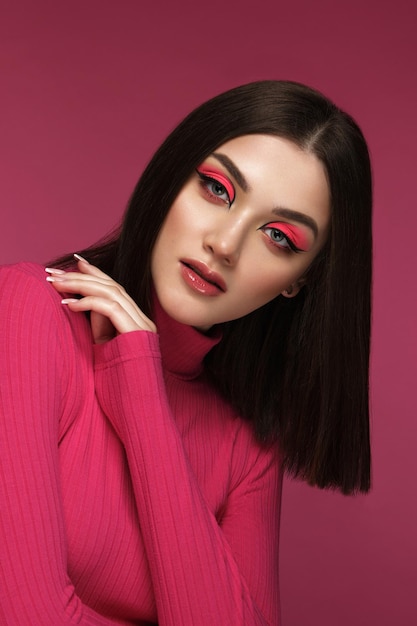 Hermosa mujer morena vestida de rosa con maquillaje de moda rosa posando en la cara de belleza del estudio