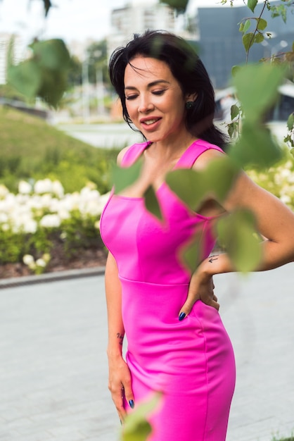 Hermosa mujer morena en vestido rosa posando en el parque