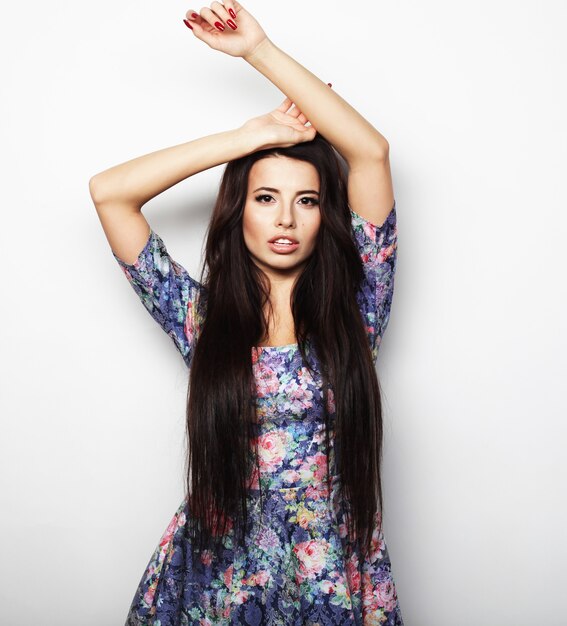 Hermosa mujer morena en vestido de verano sobre fondo blanco.