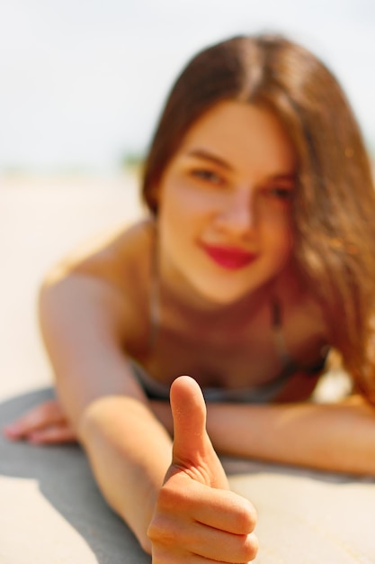 Hermosa mujer mostrando OK por su dedo en la playa