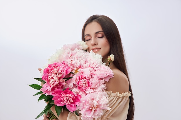 Hermosa mujer con muchas flores rosas en sus manos.