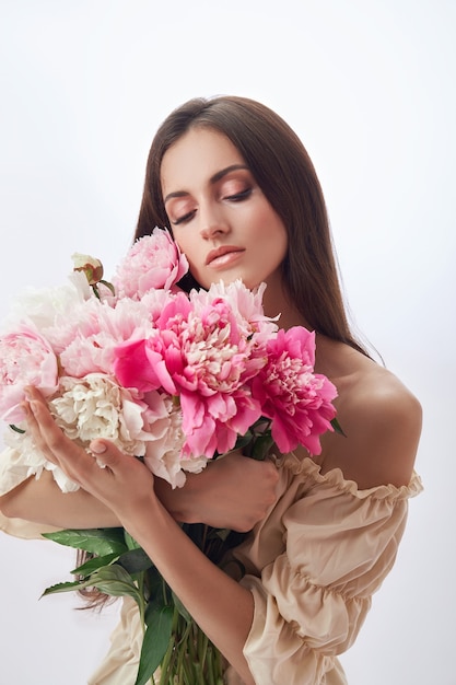 Hermosa mujer con muchas flores rosas en sus manos.