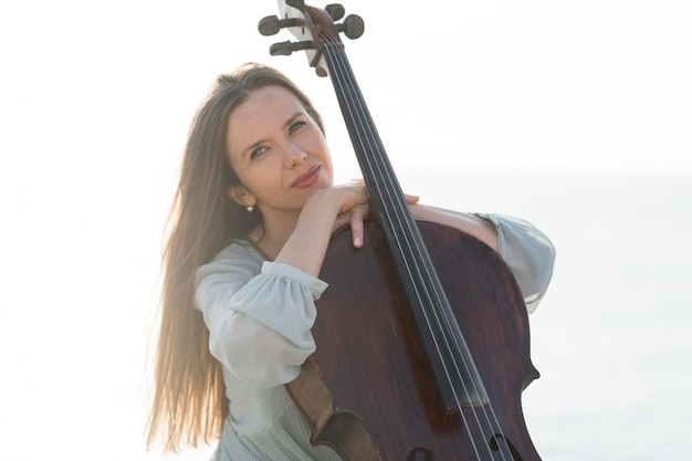 Hermosa mujer músico posando con violonchelo