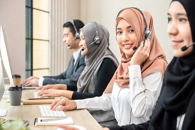 Hermosa mujer musulmana asiática trabajando en call center con equipo