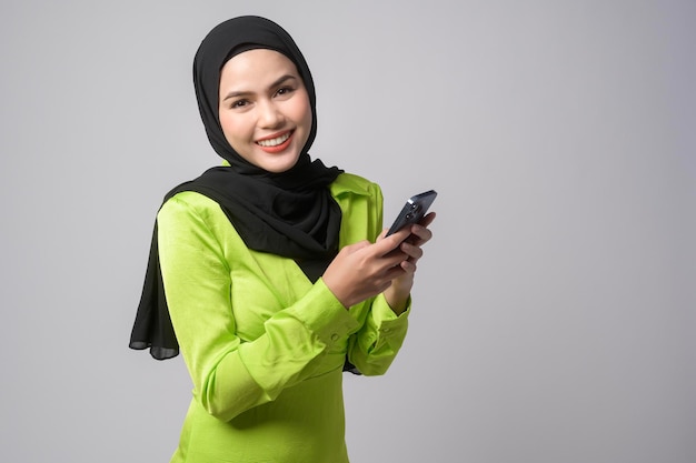 Hermosa mujer musulmana con hiyab usando un teléfono inteligente sobre el concepto de tecnología de fondo blanco x9x9