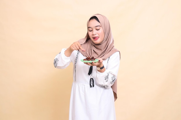 Una hermosa mujer musulmana de Indonesia con un hijab con una expresión deliciosa recoge y trae algunos
