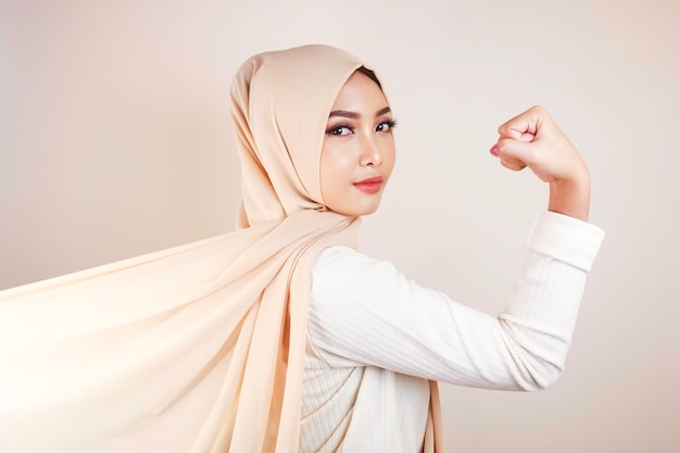 Hermosa mujer musulmana joven fuerte aislada sobre la pared de fondo blanco que muestra bíceps