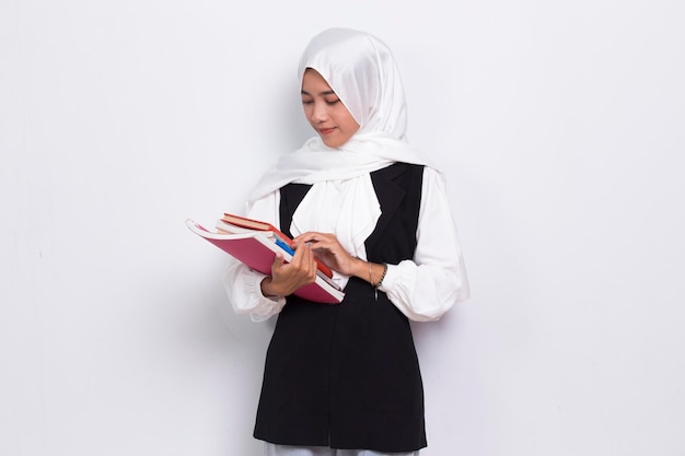 Hermosa mujer musulmana de negocios asiáticos abraza un puño de libro y tumb up ok aislado sobre fondo blanco.