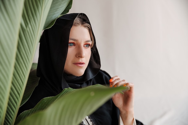 Hermosa mujer musulmana en vestido tradicional árabe abaya sobre fondo gris