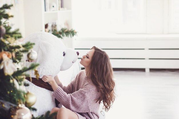 Hermosa mujer en navidad interior besando a osito de peluche