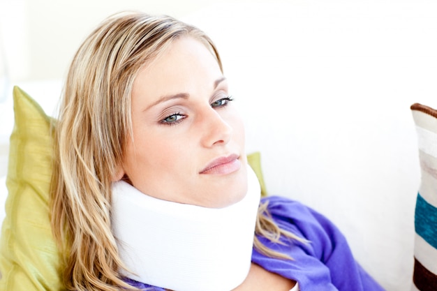 Hermosa mujer con neckbrace acostado en un sofá