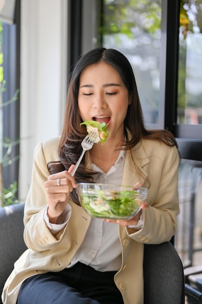 Hermosa mujer de negocios asiática con brunch disfrutando de comer una ensaladera saludable en el café