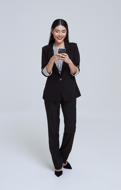 Hermosa mujer de negocios asiática usando teléfono móvil y feliz celebración sobre fondo blanco de estudio