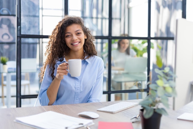 Foto hermosa mujer de negocios bebiendo café mientras trabaja en la computadora el colega está en el fondo