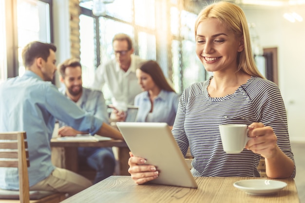 Hermosa mujer de negocios está bebiendo café y sonriendo.