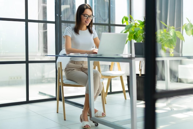 Hermosa mujer de negocios caucásica está trabajando usando una tableta digital mientras está sentada en una oficina creativa