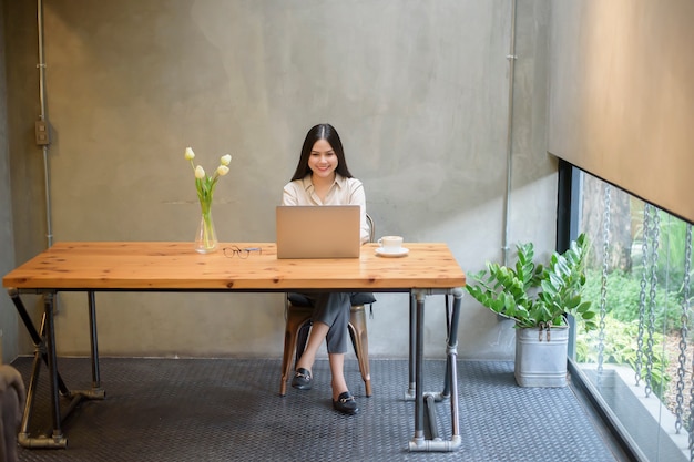 Hermosa mujer de negocios está trabajando con la computadora portátil en la cafetería