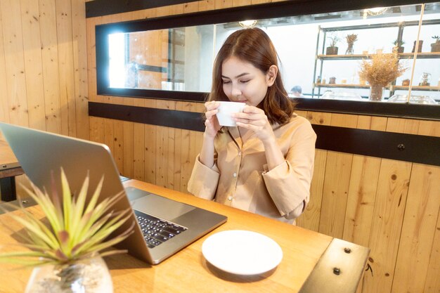 Hermosa mujer de negocios está trabajando con su computadora portátil en la cafetería