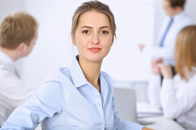 Hermosa mujer de negocios en el fondo de la gente de negocios durante la reunión