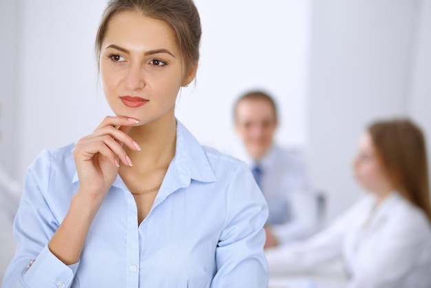 Hermosa mujer de negocios en el fondo de la gente de negocios durante la reunión