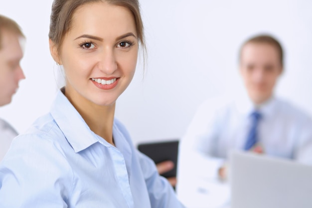 Hermosa mujer de negocios en el fondo de la gente de negocios durante la reunión