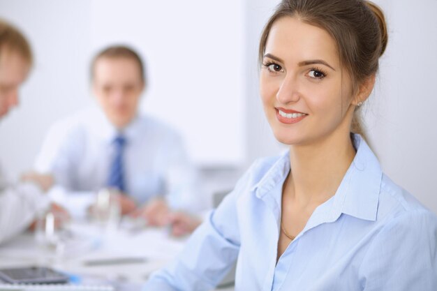 Hermosa mujer de negocios en el fondo de la gente de negocios durante la reunión