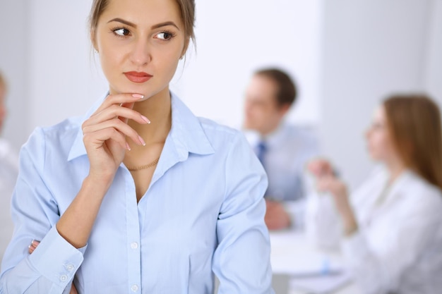 Hermosa mujer de negocios en el fondo de la gente de negocios durante la reunión