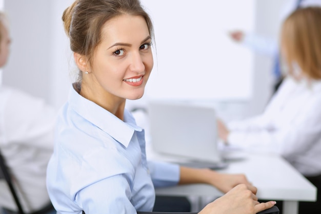 Hermosa mujer de negocios en el fondo de la gente de negocios durante la reunión