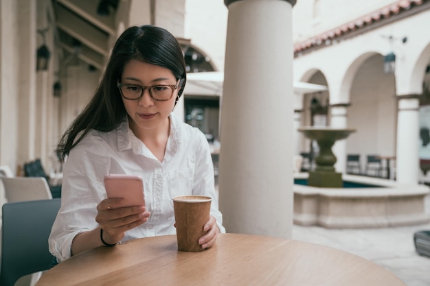 hermosa mujer de negocios leyendo por teléfono mientras está sentada en un café de algún lugar.