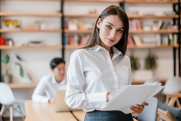 Foto hermosa mujer de negocios en la oficina de la empresa moderna con papeles de trabajo