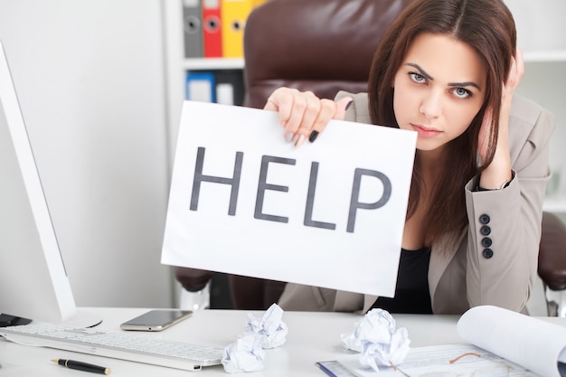 La hermosa mujer de negocios en la oficina pide ayuda.