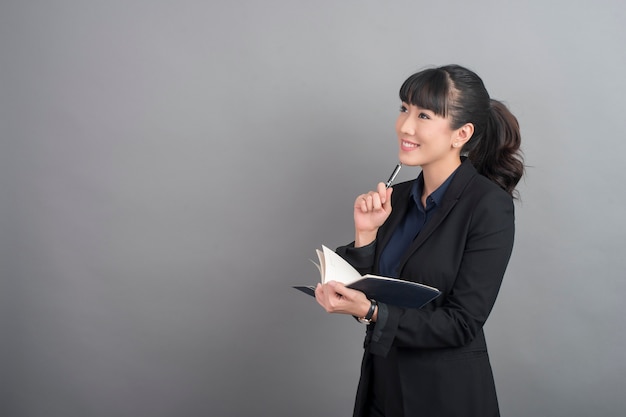 Hermosa mujer de negocios pensando en fondo gris