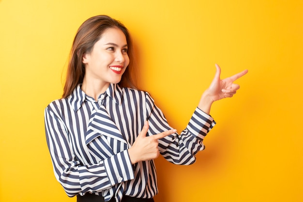 Hermosa mujer de negocios presenta algo sobre fondo amarillo