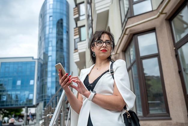 Hermosa mujer de negocios que usa teléfono móvil para reproducir redes sociales en edificios del centro