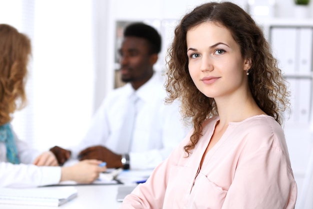 Foto hermosa mujer de negocios en la reunión en el fondo de la oficina de color blanco