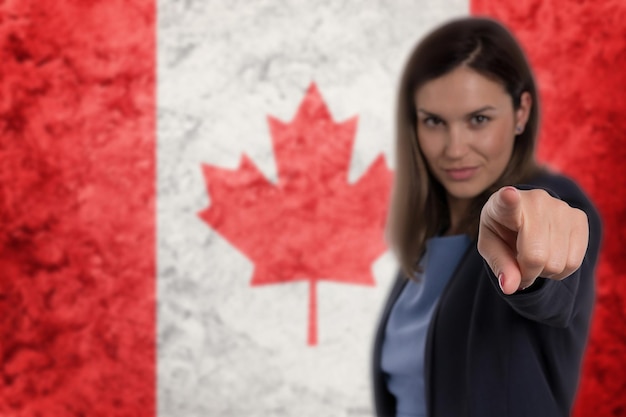 Hermosa mujer de negocios señalándote con el dedo el fondo de la bandera de Canadá.