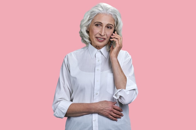 Foto hermosa mujer de negocios senior hablando por teléfono celular sobre fondo rosa mujer madura usando p móvil