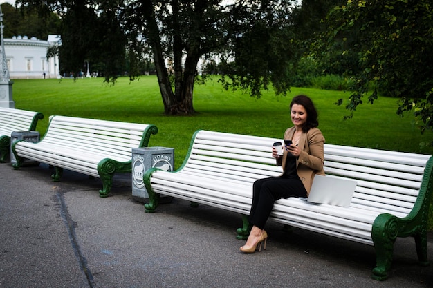 Hermosa mujer de negocios sentada en el parque en un banco