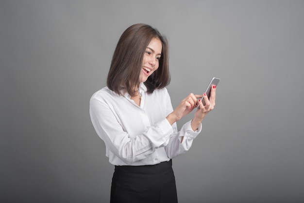 Hermosa mujer de negocios con smartphone sobre fondo gris