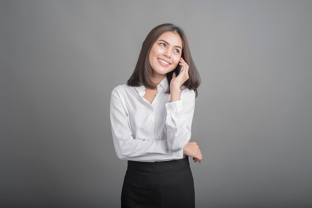 Hermosa mujer de negocios con smartphone sobre fondo gris