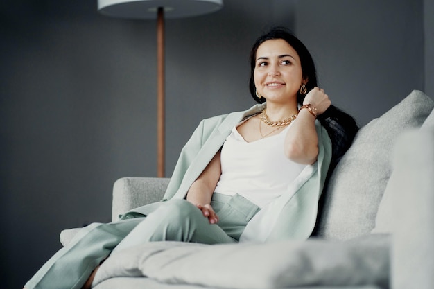 Hermosa mujer de negocios trabajando sentada en el sofá y sonriendo Oficina elegante vestida