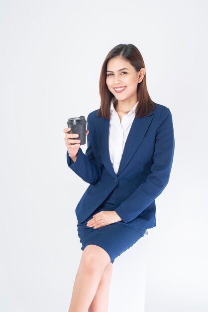 Hermosa mujer de negocios en traje azul está tomando café