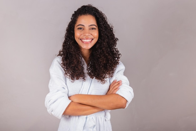 Hermosa mujer negra brasileña con albornoz y toalla cabello rizado spa centro de belleza cuidado del cabello brazos cruzados