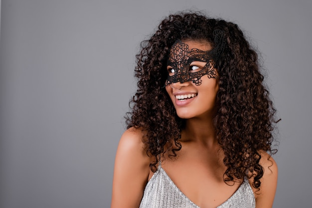 Hermosa mujer negra con elegante máscara de mascarada aislada sobre gris