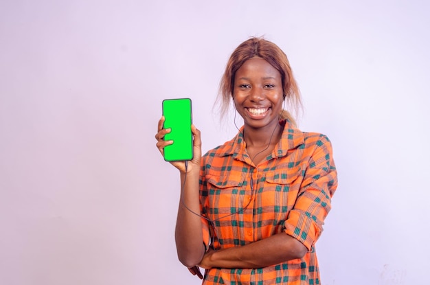 Hermosa mujer negra muestra la pantalla de su teléfono mientras se siente feliz y emocionada con el concepto publicitario centrado en su rostro