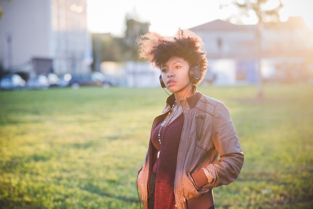 hermosa mujer negra de pelo rizado escuchando música