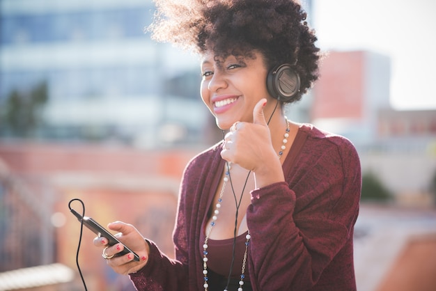 hermosa mujer negra de pelo rizado escuchando música