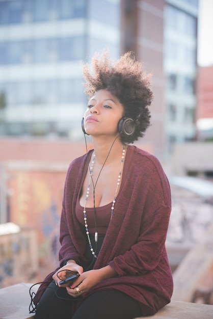 hermosa mujer negra de pelo rizado escuchando música