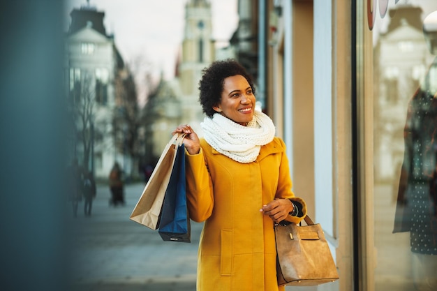 Hermosa mujer negra sonriente caminando y comprando en la ciudad.