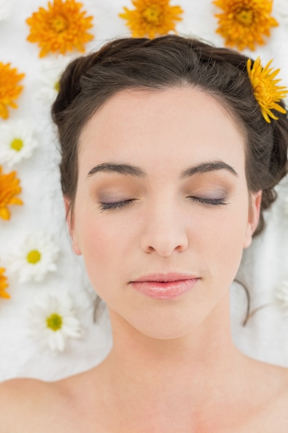 Hermosa mujer con los ojos cerrados y flores en el salón de belleza